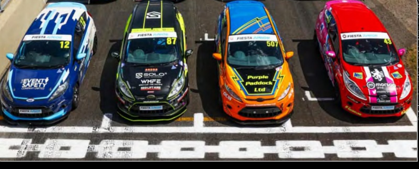 Four liveried Fiesta Junior race cars lined up on the grid